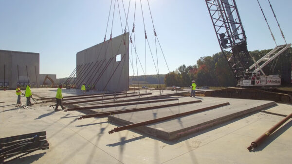 Construction crew putting up cement wall with crane
