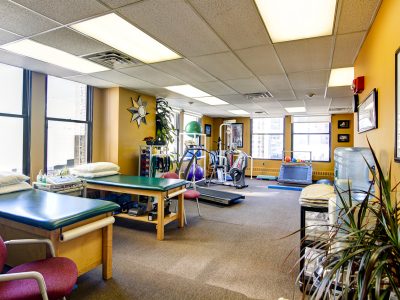 Row of treatment tables in a green-walled physical therapy treatment room.