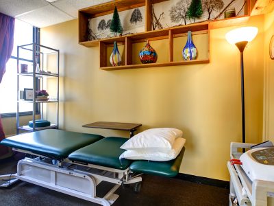 Private treatment table beside a shuttered window in a physical therapy clinic.
