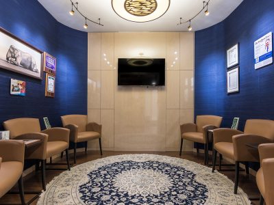 Patient waiting room with seating, a wall-mounted television, and warm lighting at a rehab clinic.
