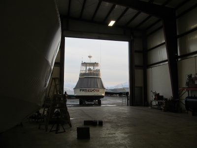 Boat positioned in the doorway of a marine storage and service building.