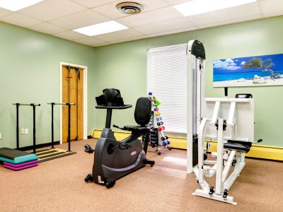 Rehabilitation exercise room with a stationary bike and therapy equipment.