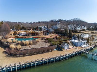 Luxury waterfront home being framed beside a private dock and pool in Northport, New York, seen from the air.