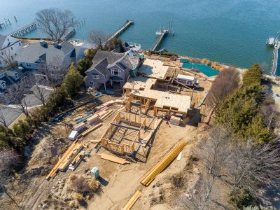 Wood framing of a waterfront home taking shape next to a dock and open water in Northport, New York.