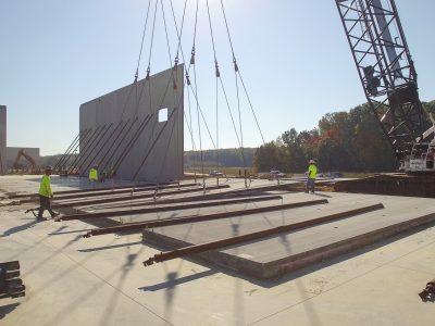 Construction crew putting up cement wall with crane