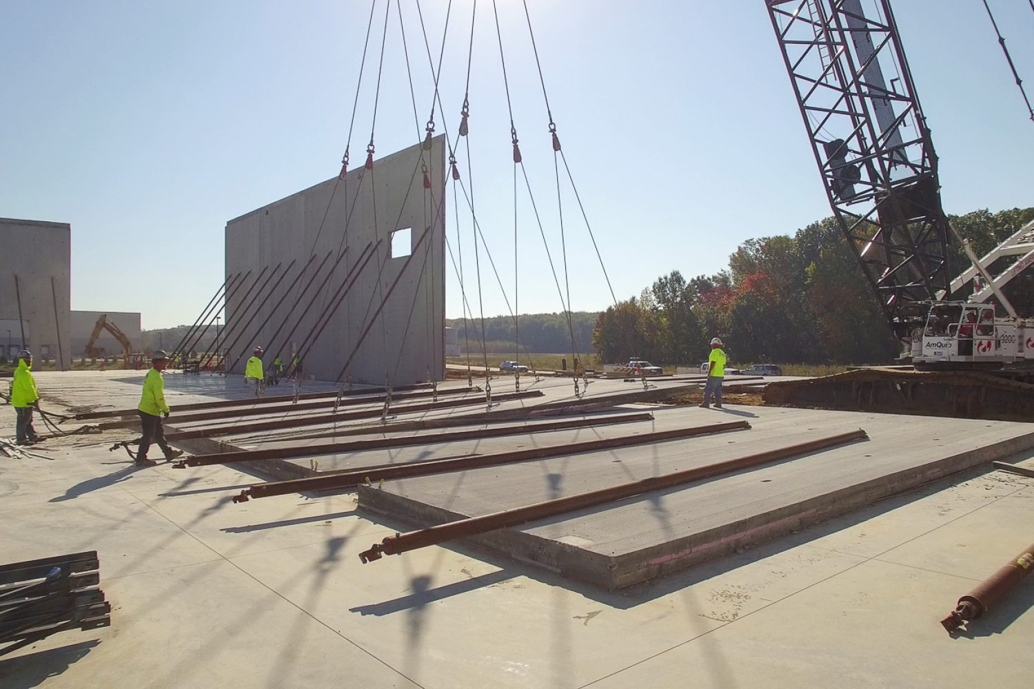 Construction crew putting up cement wall with crane